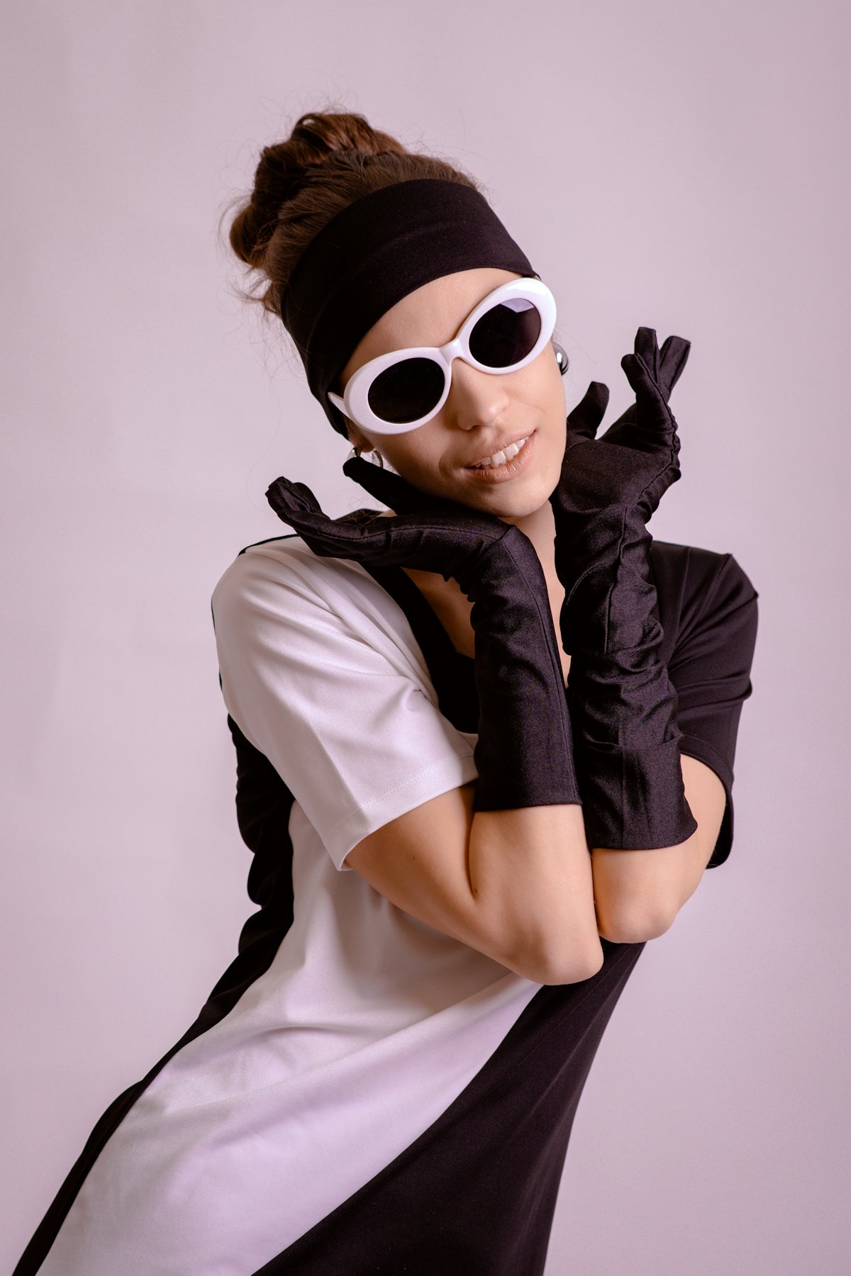 Woman in black and white dress with gloves and sunglasses.