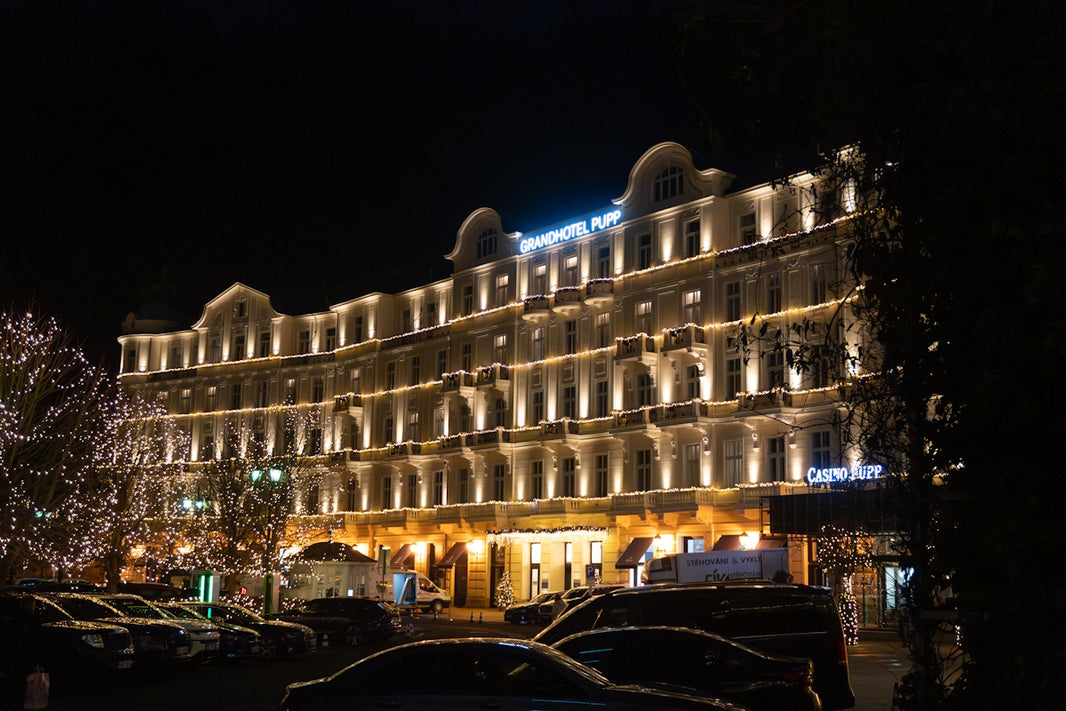 Grand hotel illuminated at night with parked cars