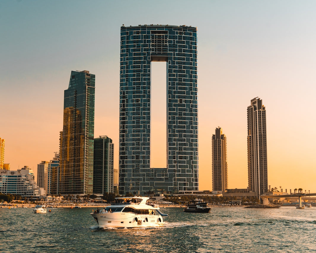 Modern skyscrapers and yachts on the water at sunset.