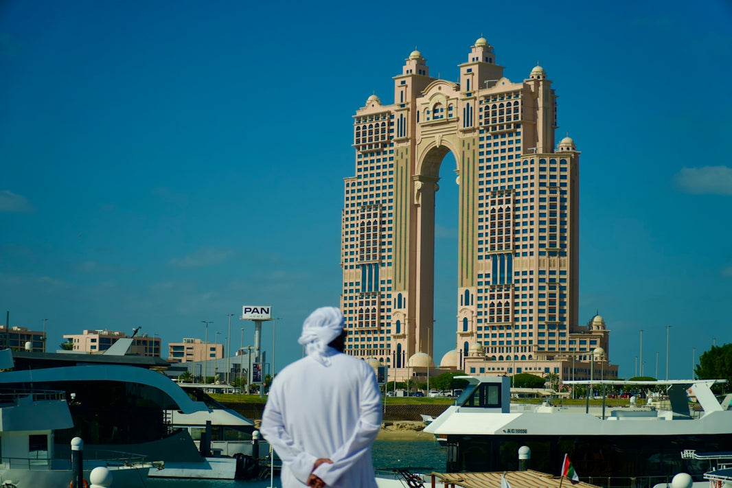Man in traditional clothing looks at modern skyscraper