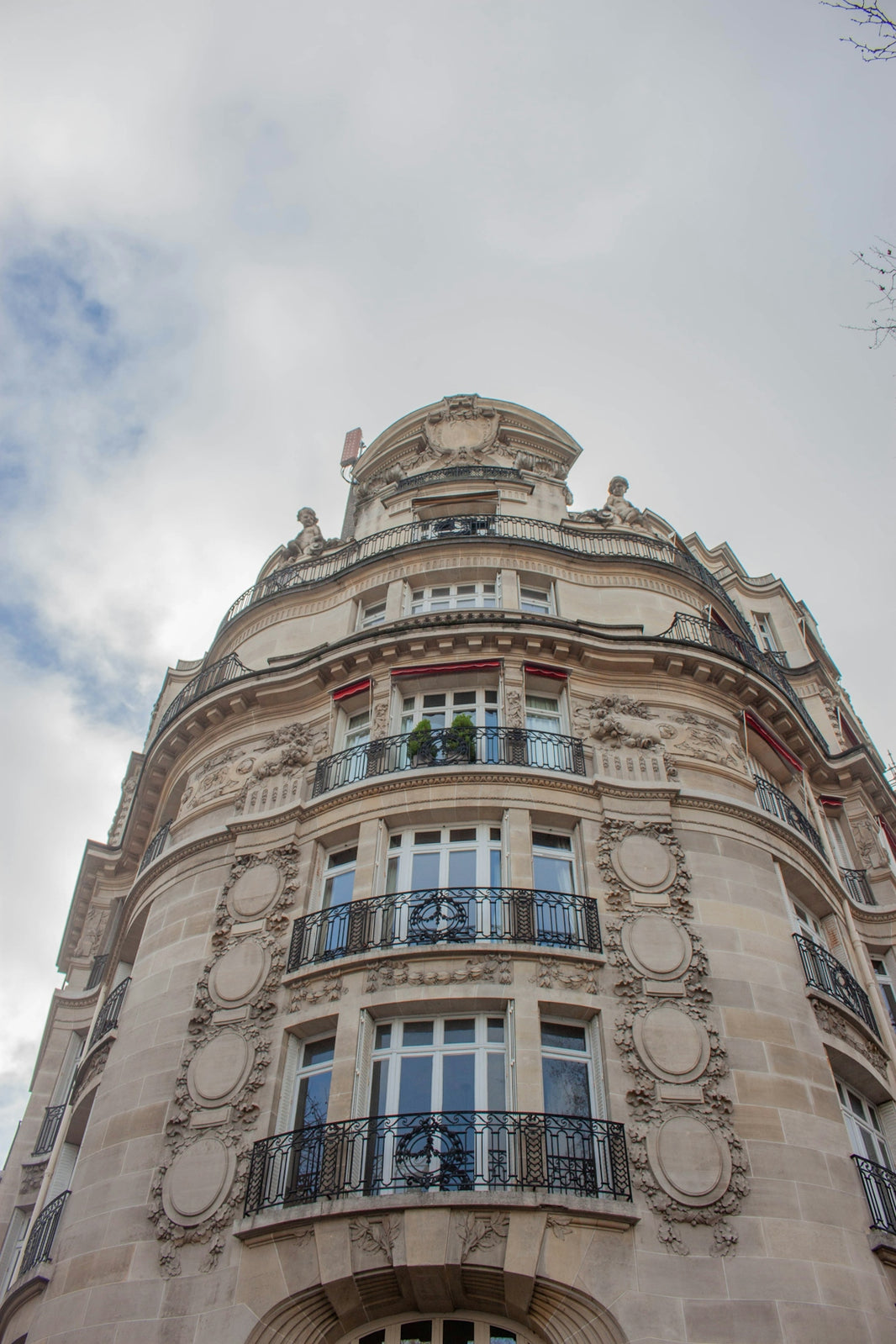 Ornate parisian building with balconies against cloudy sky