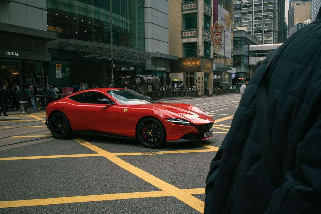 Red sports car driving on a city street.