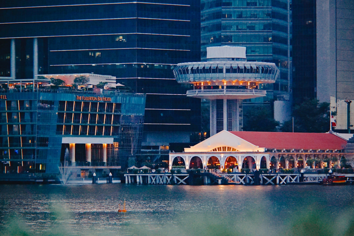 Modern buildings overlooking a calm body of water at dusk.