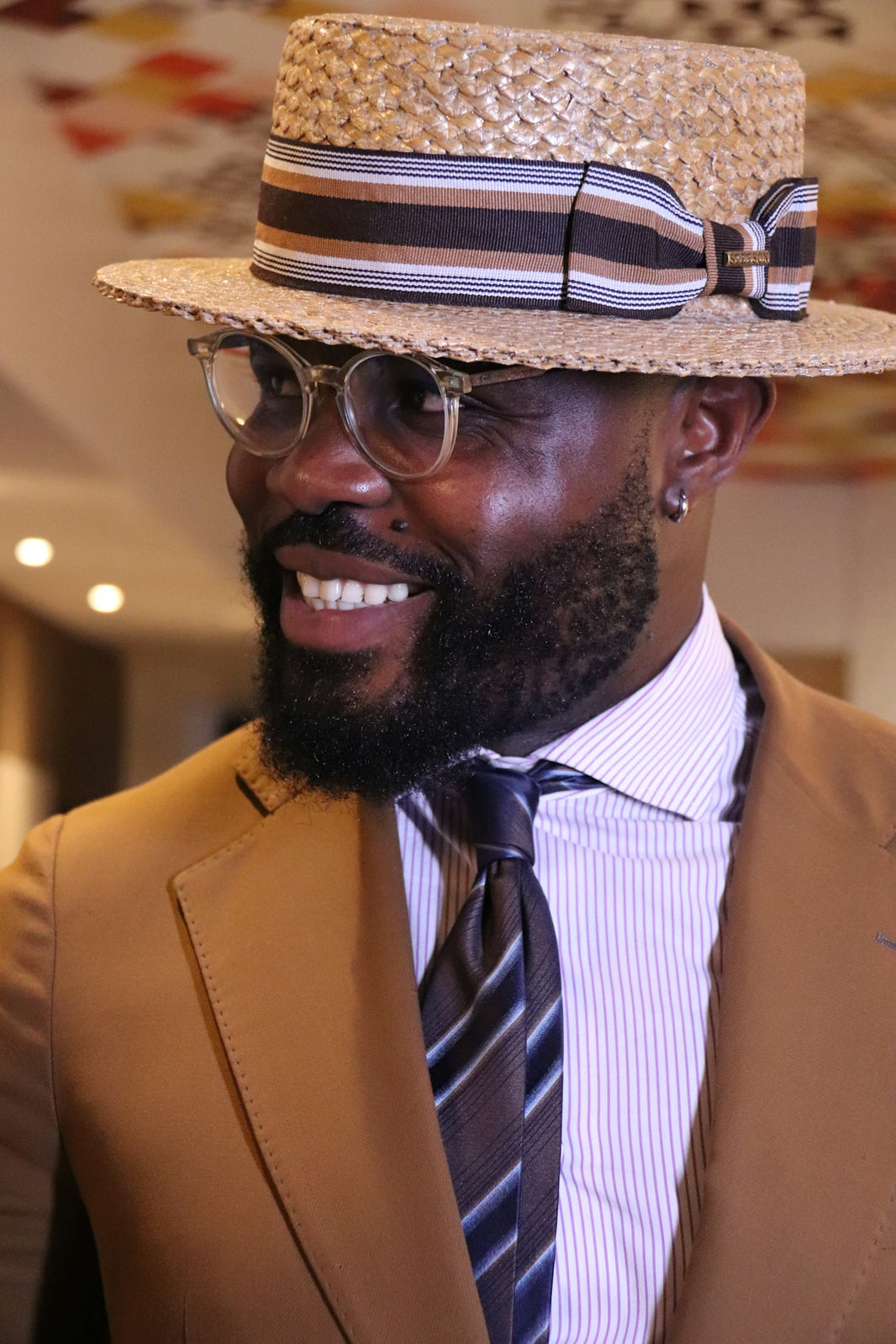 Man wearing a straw hat and suit smiles