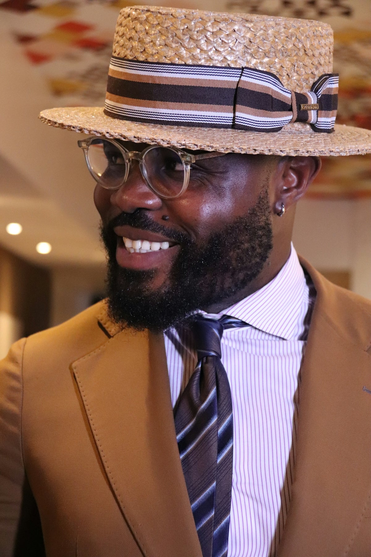 Man wearing a straw hat and suit smiles