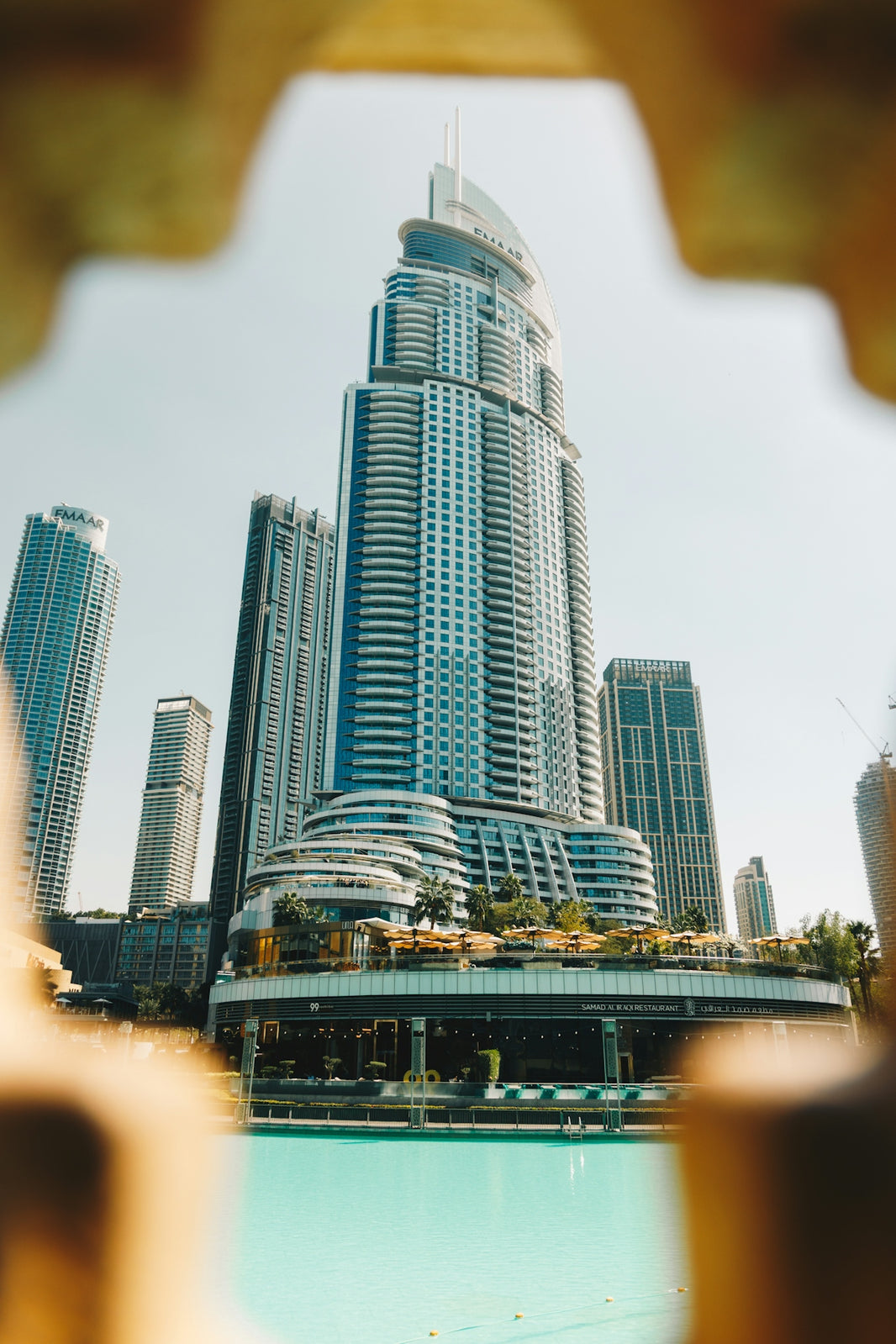 Modern skyscrapers and a turquoise pool on a sunny day.