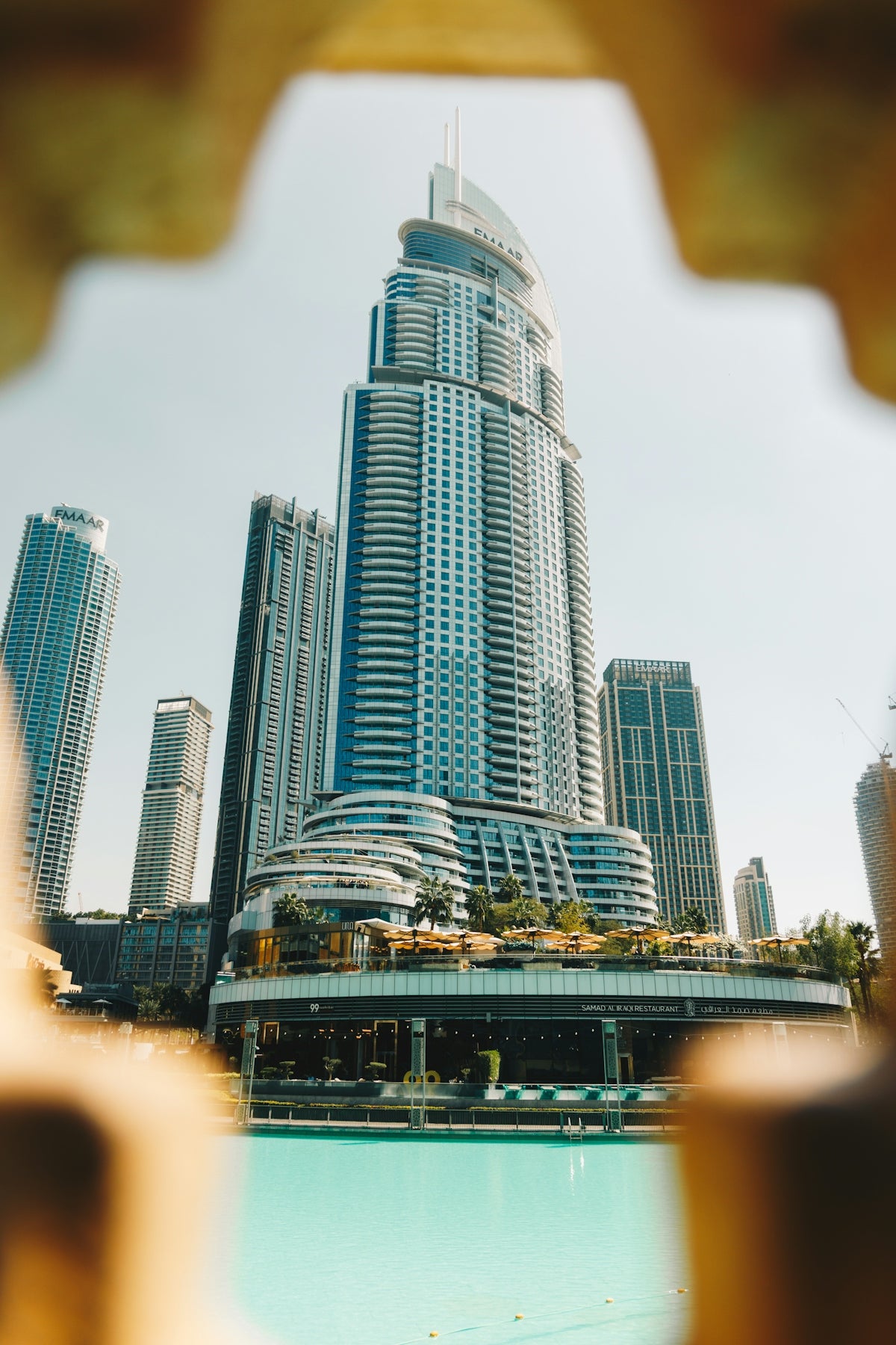 Modern skyscrapers and a turquoise pool on a sunny day.