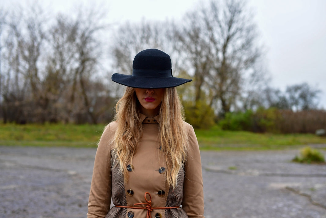 Woman in a wide-brimmed hat and coat outdoors