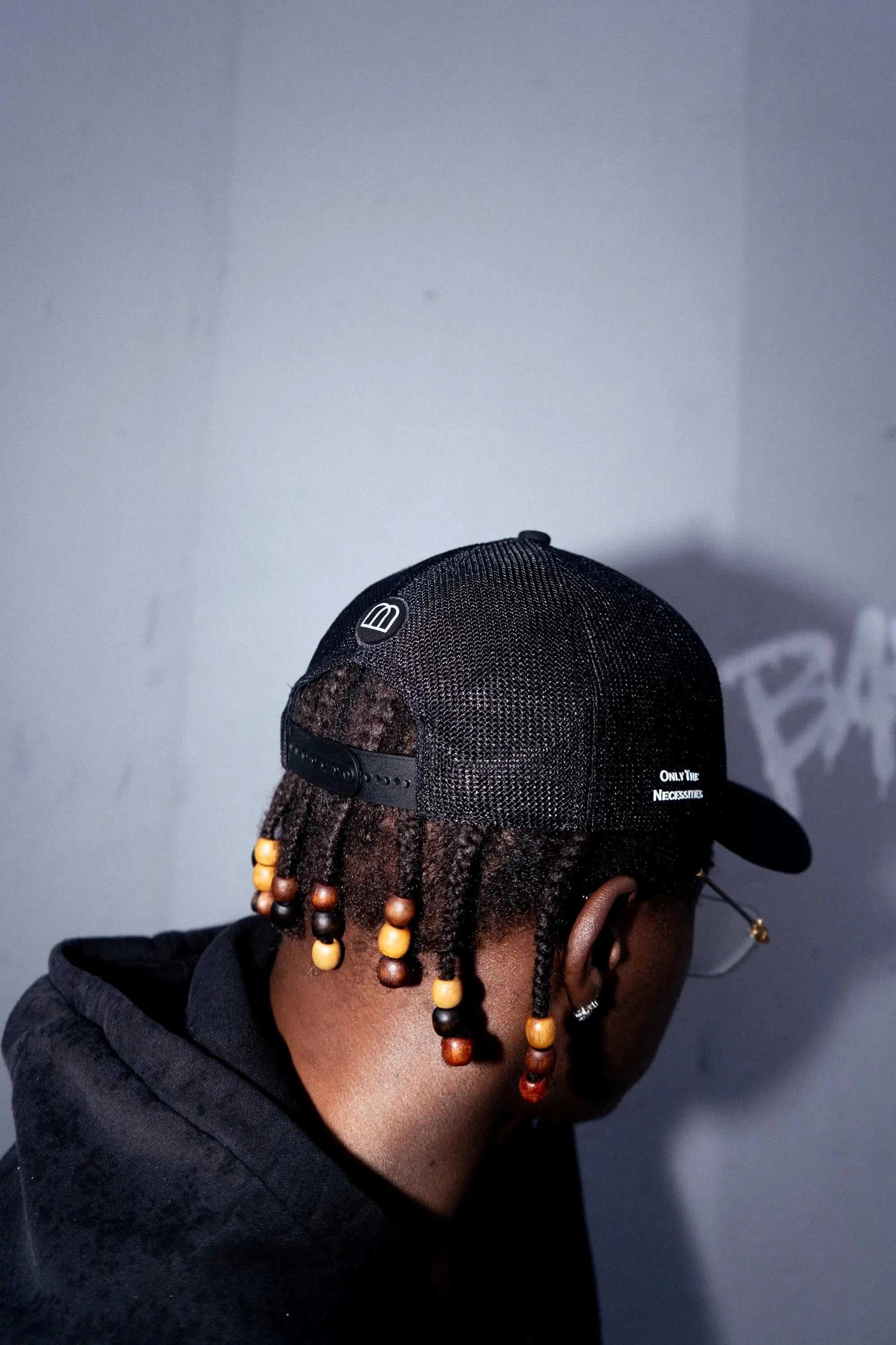 Dirty Martini Trucker Hat in black with mesh back and signature patch worn by model with beaded hairstyle