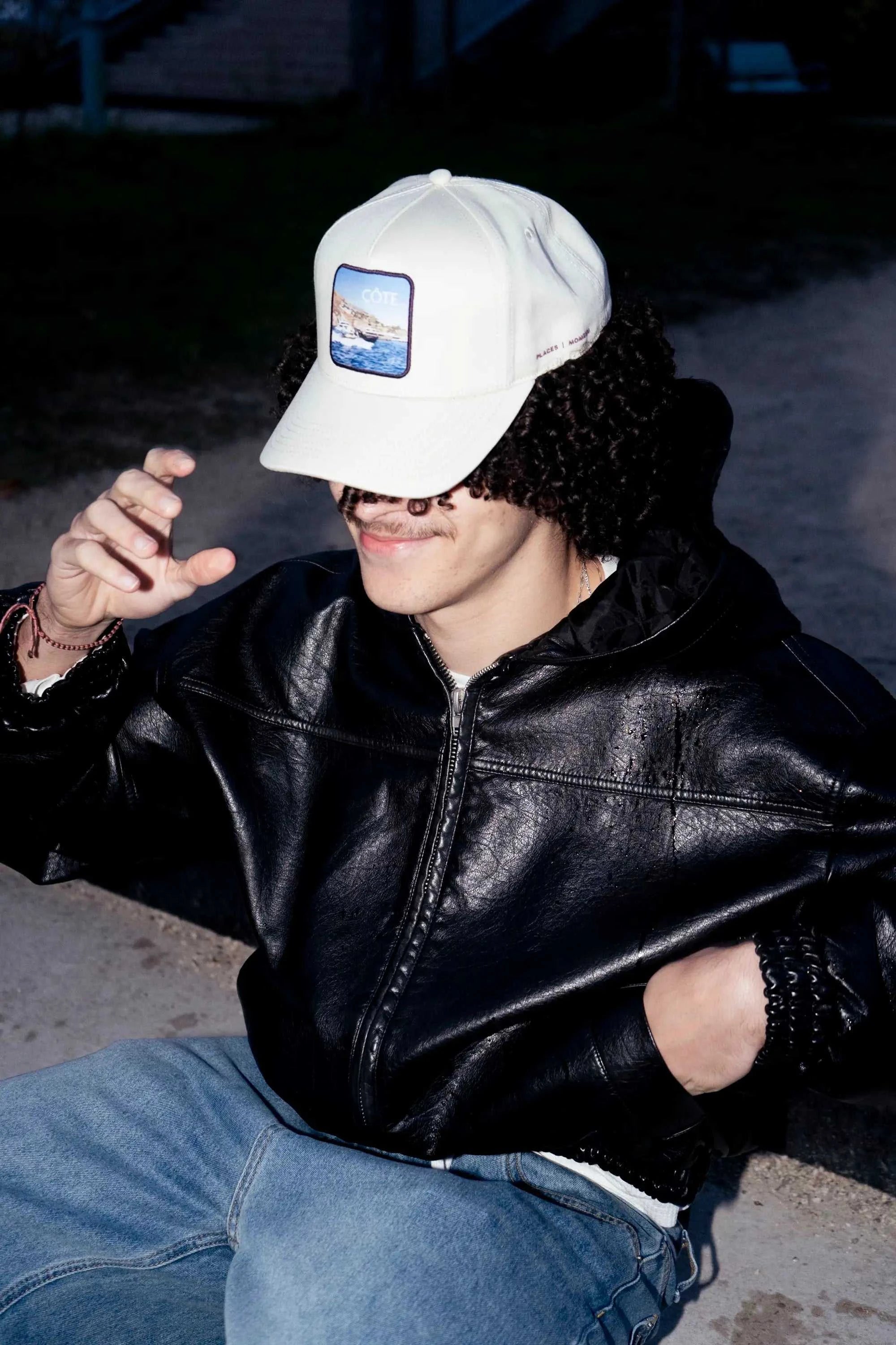 Côte Baseball Cap in Isla Crema with curved brim, soft full-panel design, and Places | Moments patch worn by person in black leather jacket