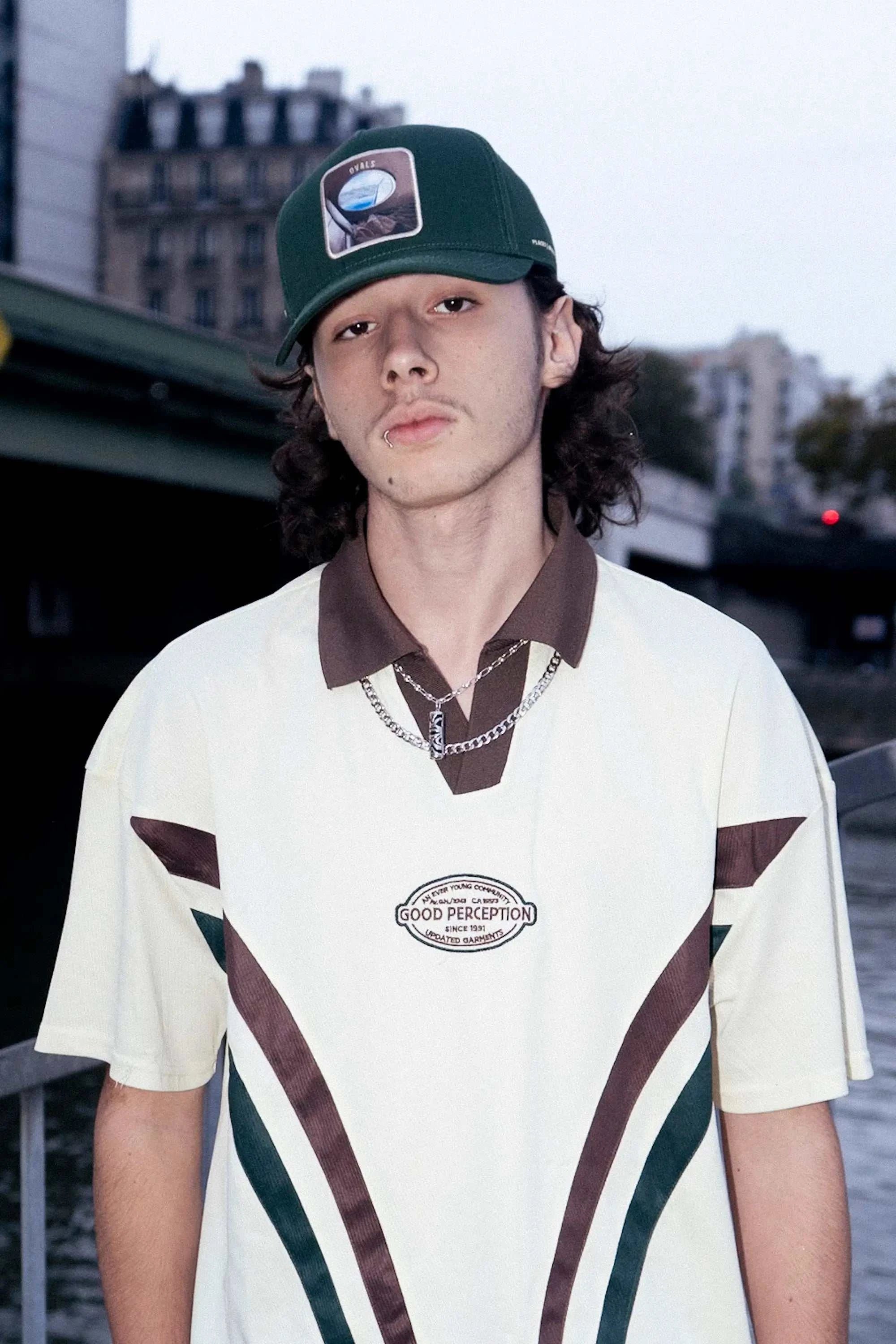 Young man wearing a deep forest-green Ovals Baseball Cap with embroidered patch, styled casually outdoors.