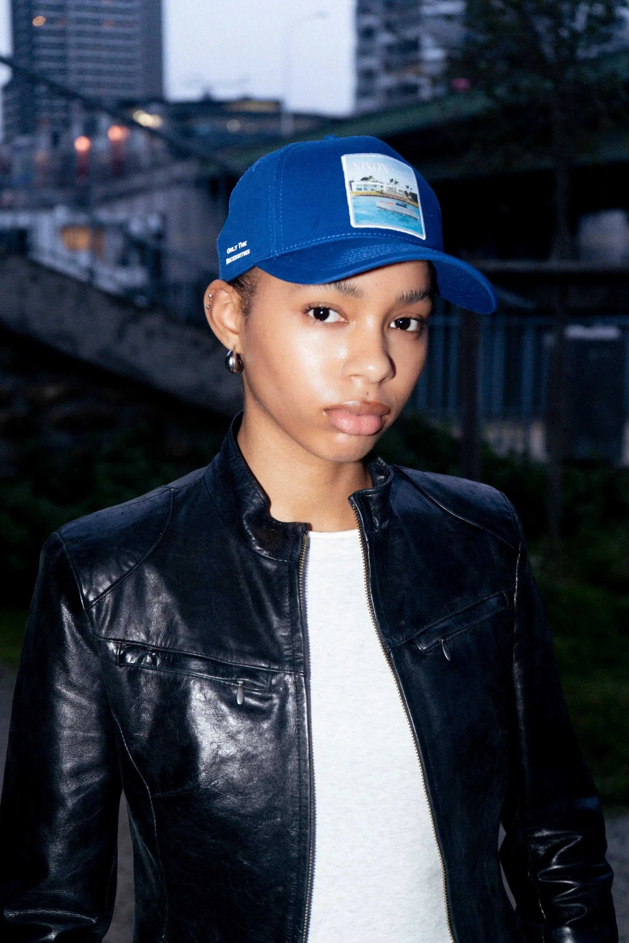 Blue Nixon Baseball Cap with Places | Moments patch worn by model in urban setting