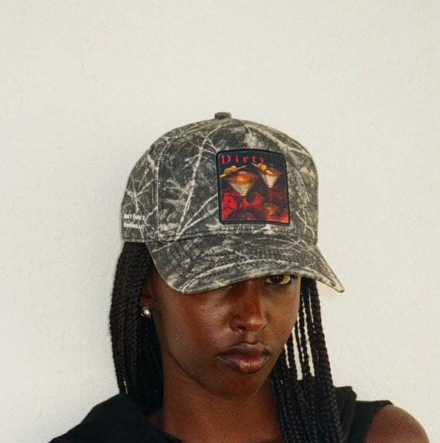 A woman wearing the Dirty Martini baseball cap in winter branch camo, front view, showing the martini and roses patch.