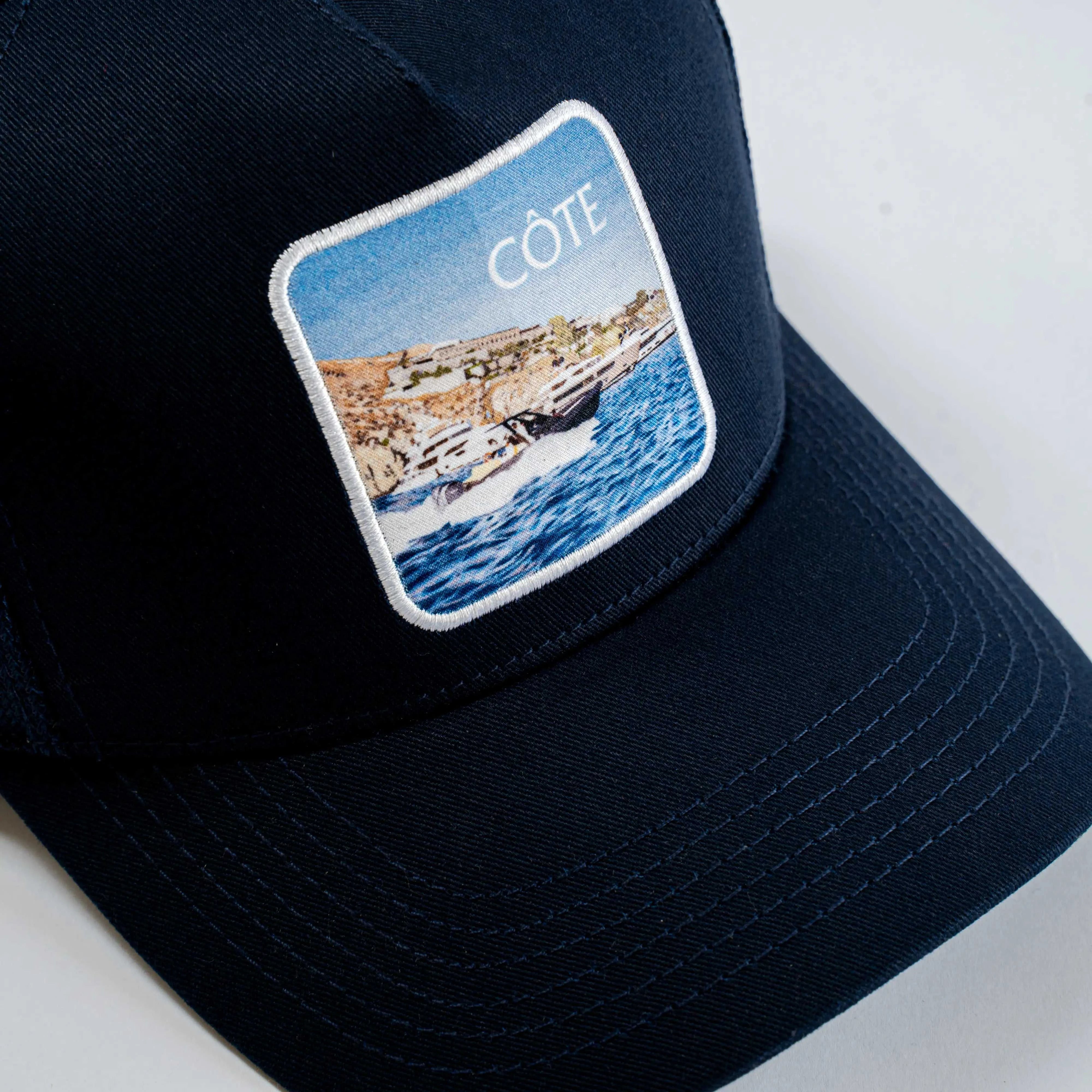 Côte Mesh-Back Trucker Hat in Indie Blue with structured front, breathable mesh back, curved brim, and Places | Moments patch