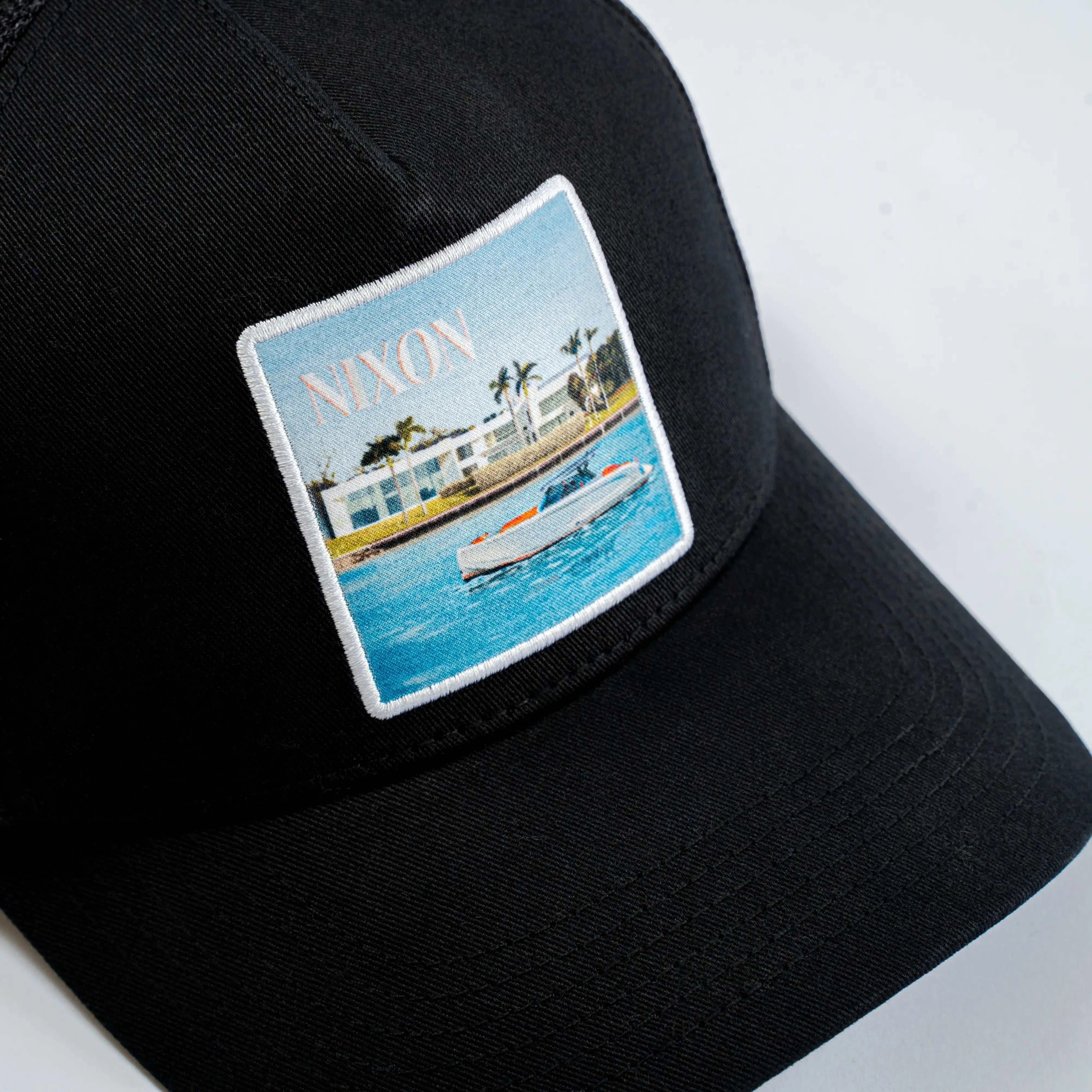 Black Nixon Mesh-Back Trucker Hat with embroidered scenic patch and curved brim