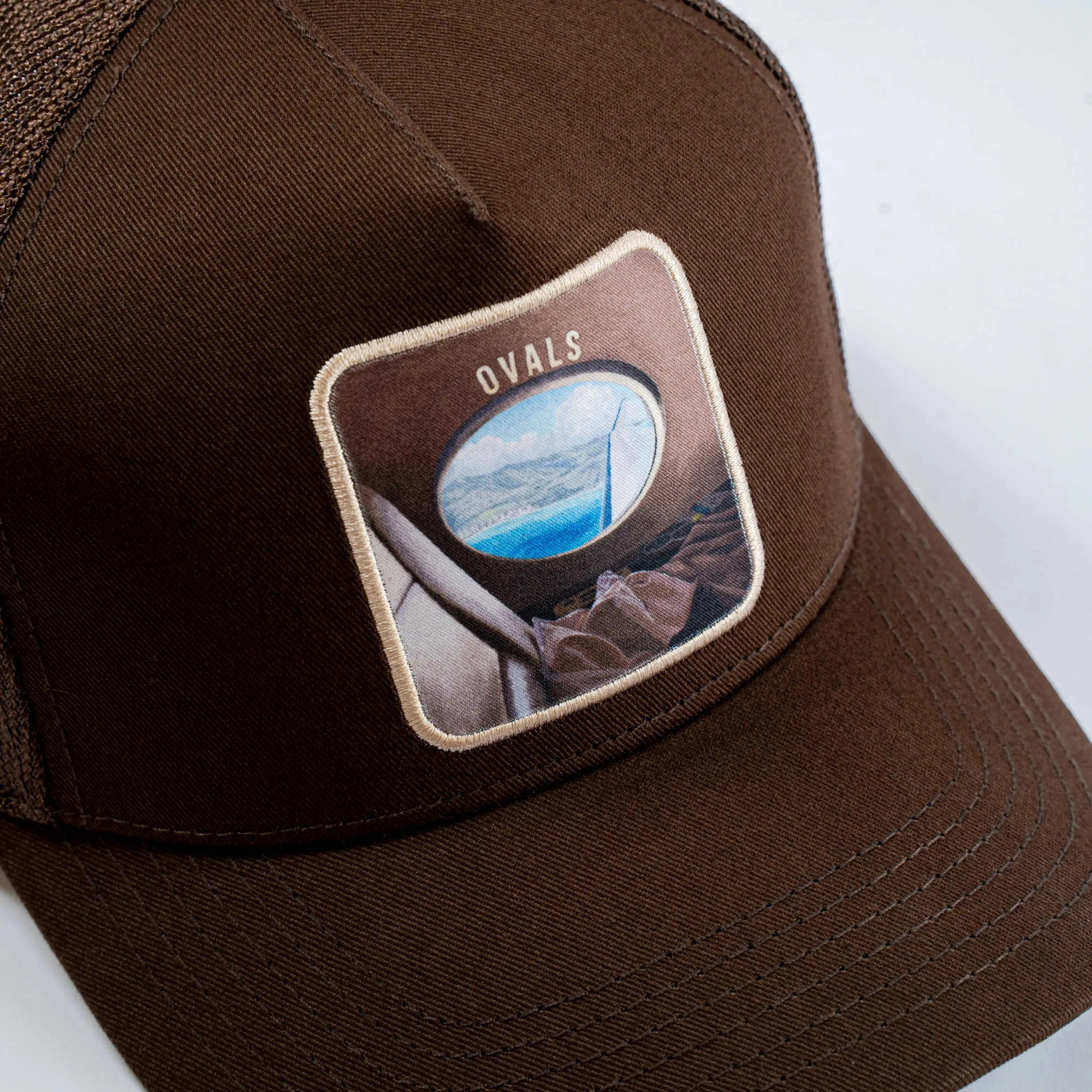Ovals Mesh-Back Trucker Hat in brown with embroidered oval window patch and breathable tan mesh back
