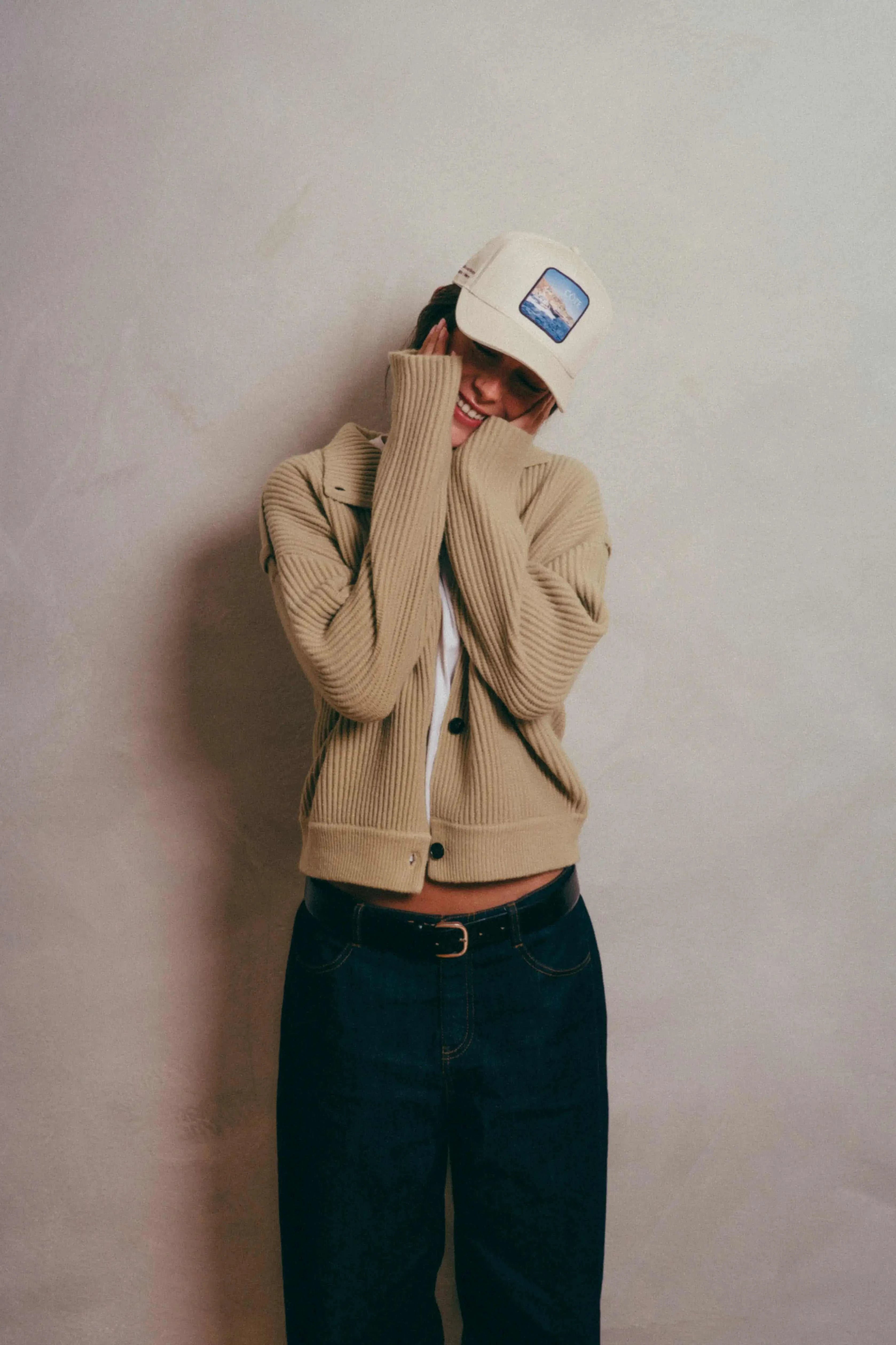 Côte Baseball Cap in Isla Crema worn with beige cardigan and dark jeans against neutral background