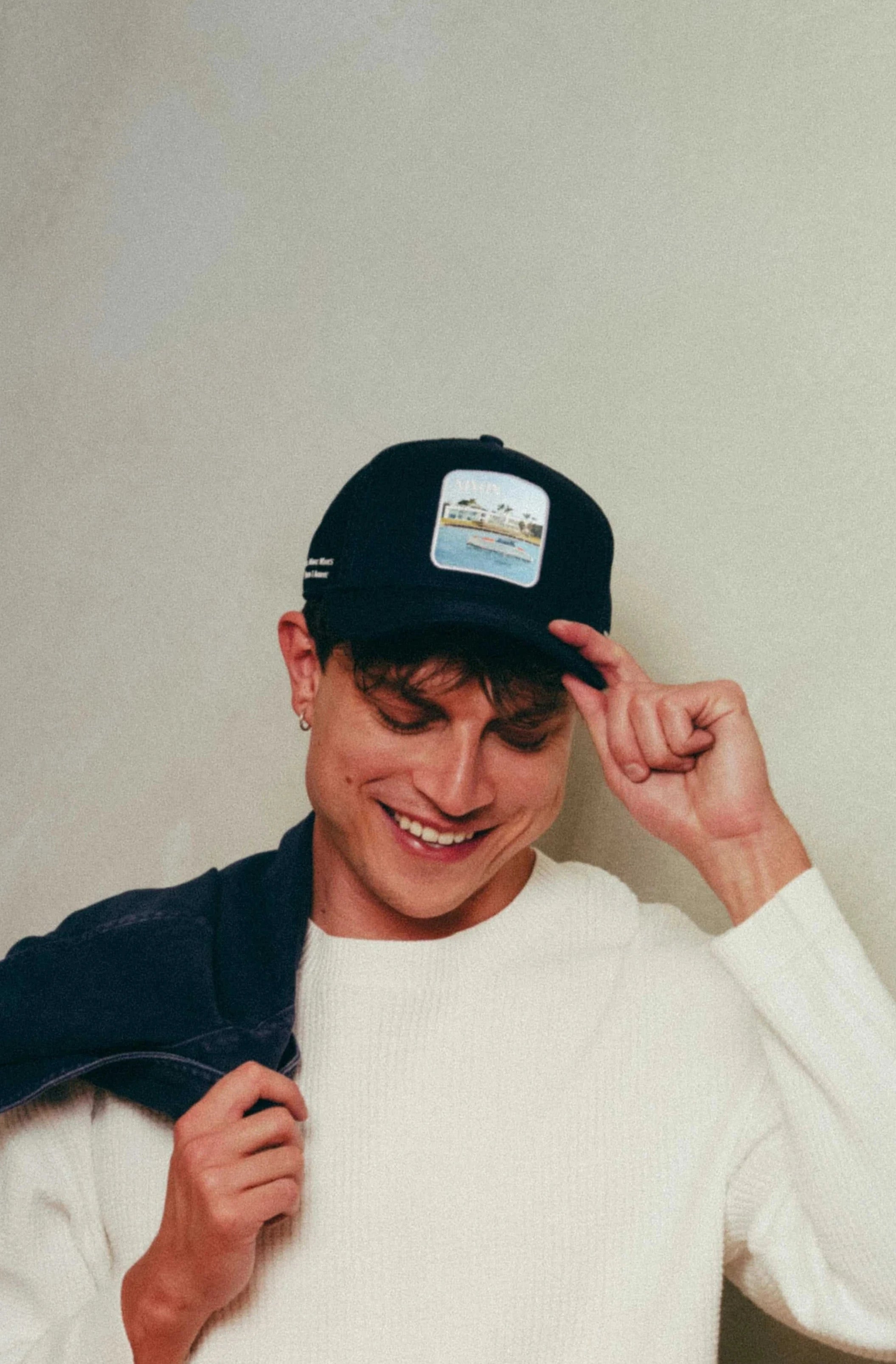 Black Nixon Mesh-Back Trucker Hat with structured front, breathable mesh, and embroidered patch worn by smiling man in casual outfit