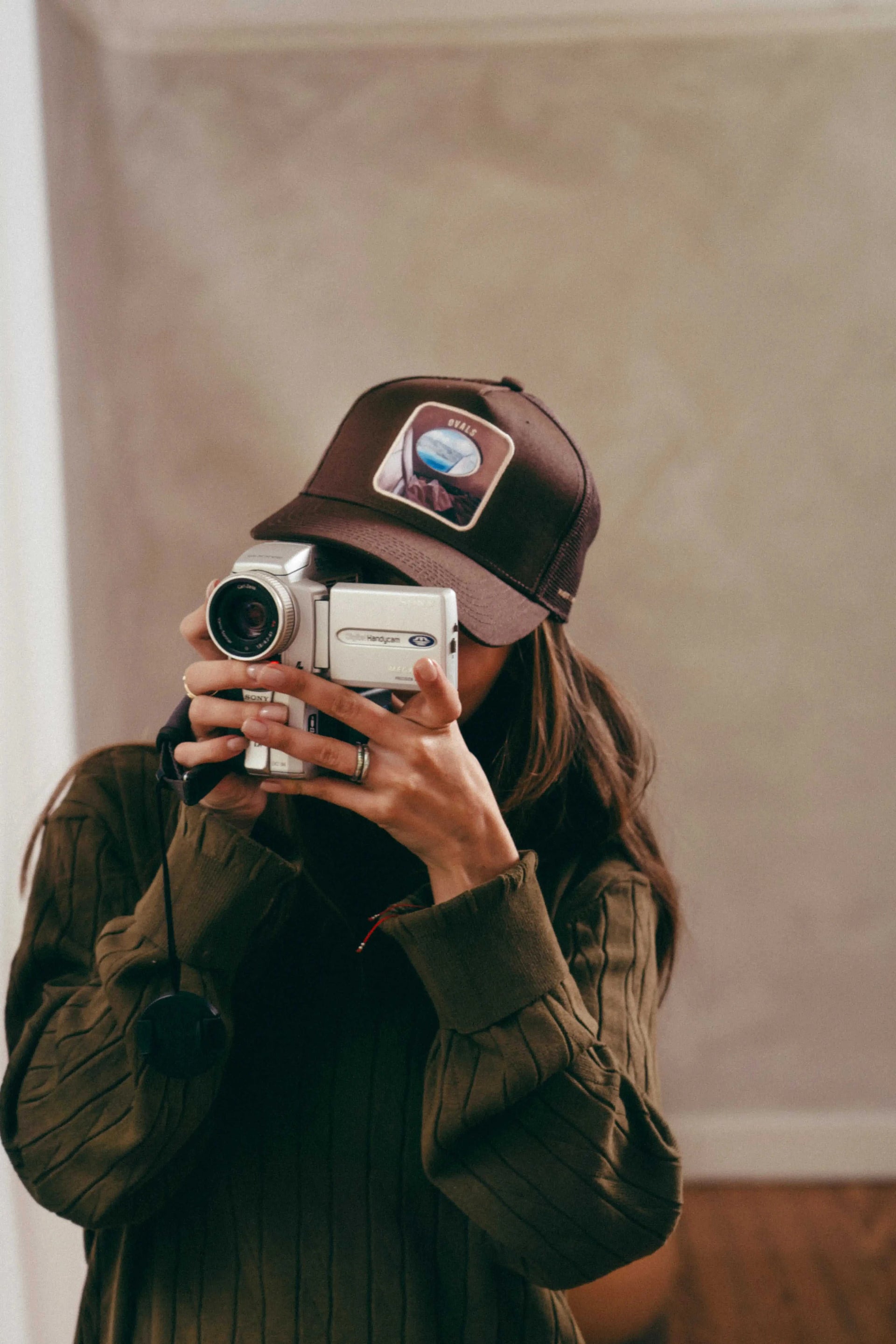 Ovals Mesh-Back Trucker Hat in chestnut with tan breathable mesh and embroidered patch worn by person holding camera