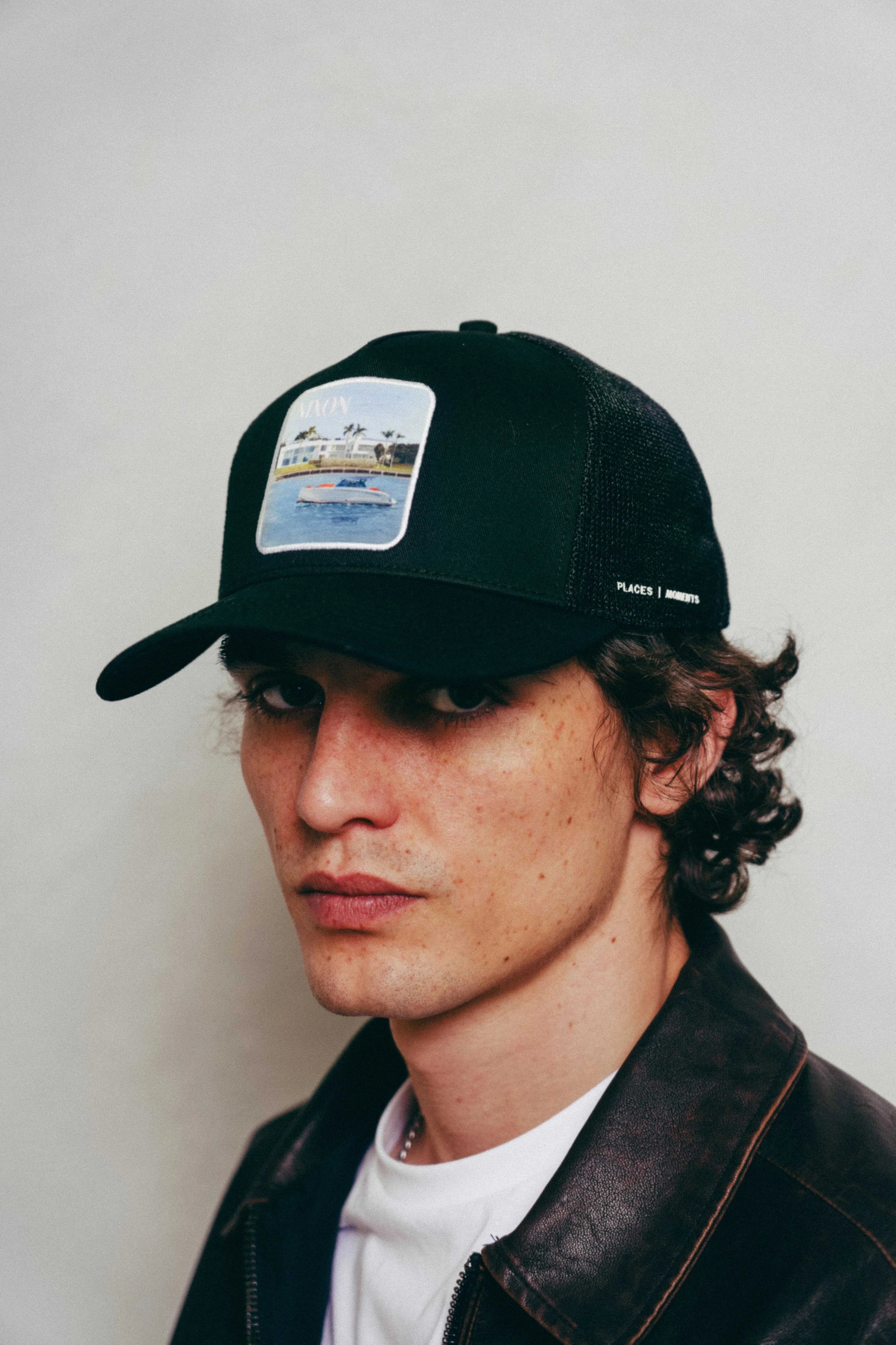 Black Nixon Mesh-Back Trucker Hat with curved brim and embroidered Places | Moments patch worn by man