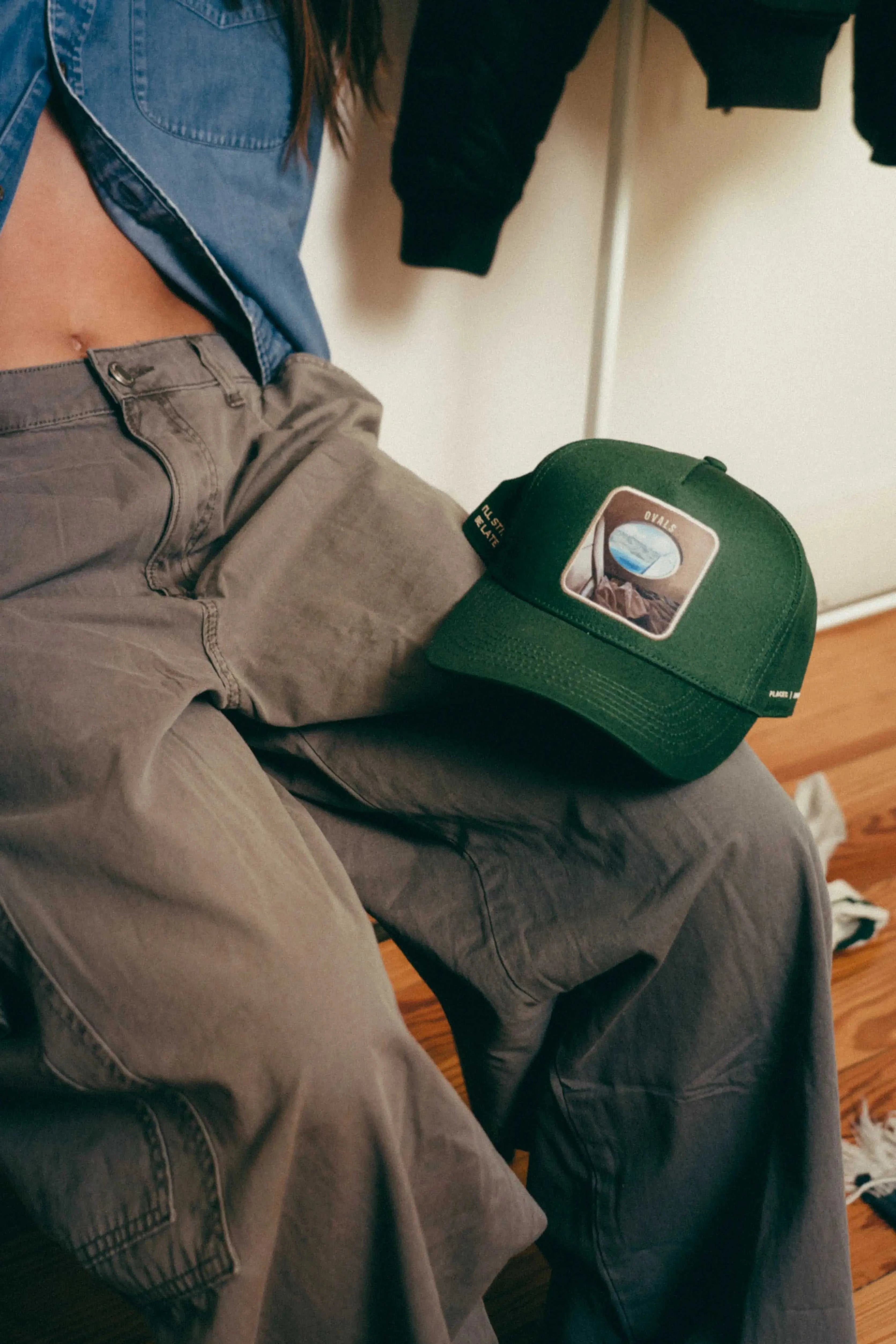 Forest green Ovals Baseball Cap with embroidered patch on gray pants and casual outfit.