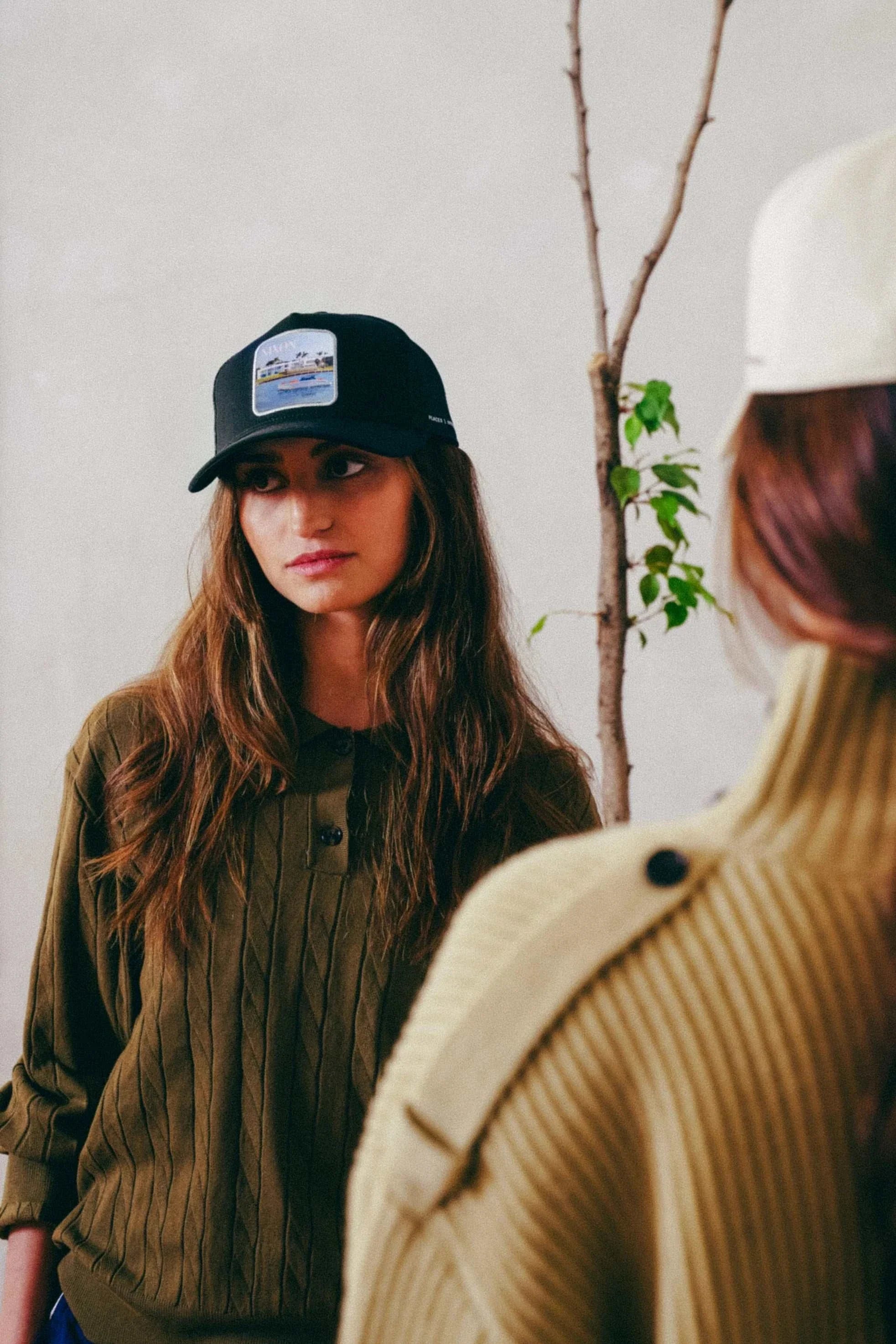 Black Nixon Mesh-Back Trucker Hat with structured front panel and curved brim worn by woman
