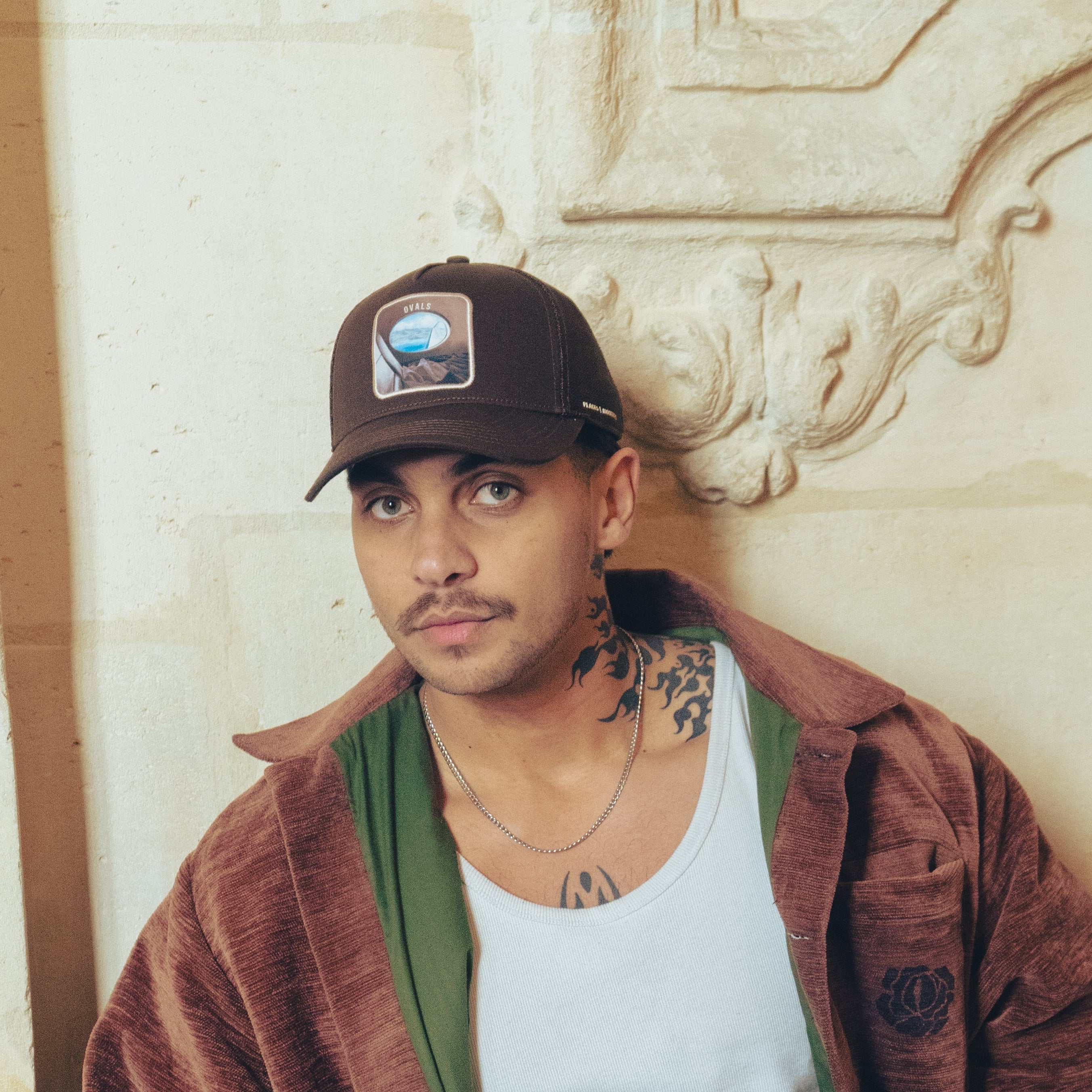 Brown Ovals Mesh-Back Trucker Hat with chestnut front, tan mesh back, curved brim, and embroidered patch